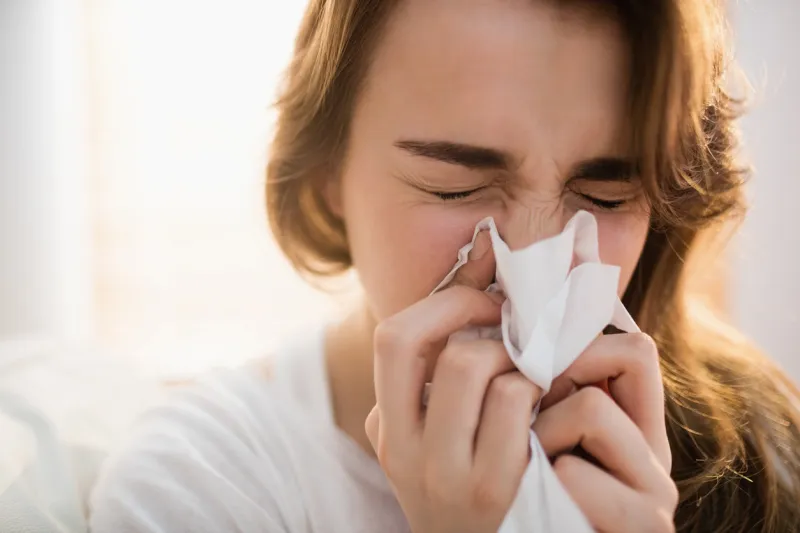 woman blowing her nose on couch in the living room