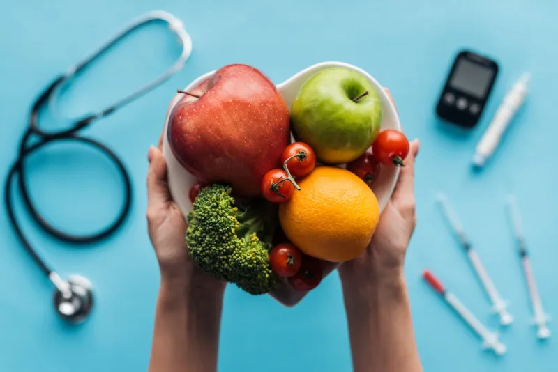 fruits and vegetables in female hands with medical equipment on blue background
