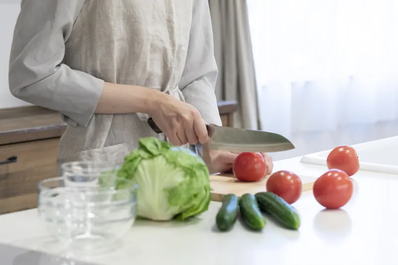 hands of a young woman cutting vegetables in the kitchen