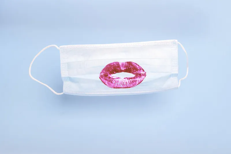 medical mask with print of female lipstick kiss lips on blue background prevention and protection of the population during an epidemic, corona virus (covid19), colds and viral flu