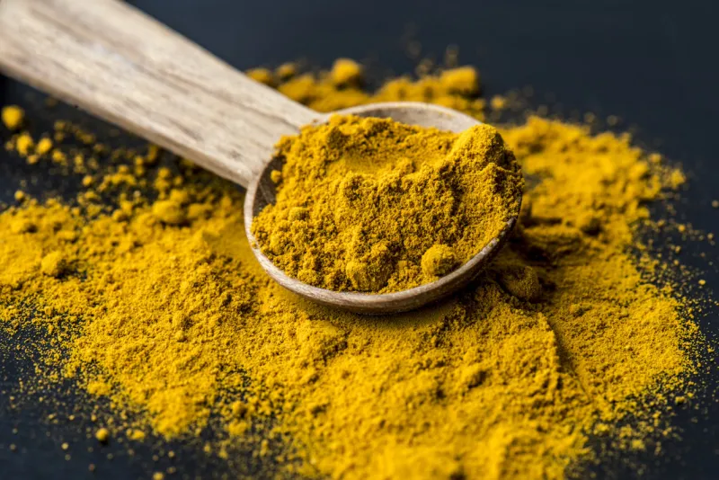 closeup of tumeric powder spice on a spoon