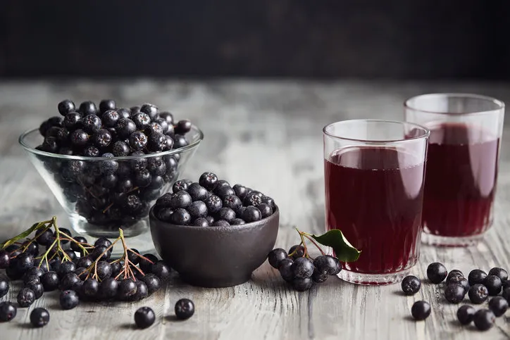 fresh aronia berries and aronia berry juice in glasses