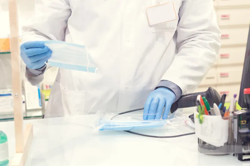 shopper in drugstore pharmacist are saling protective masks blurred background of farmacy protective measures from infection to covid-19