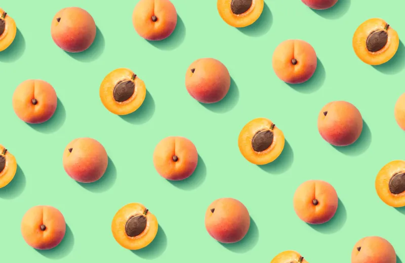 colorful fruit pattern of fresh apricots on green pastel background, top view, flat lay