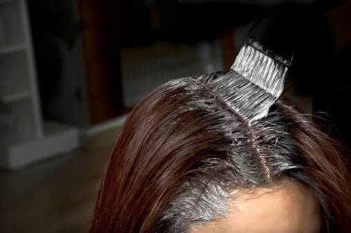 close-up of the head of a woman in the process of getting her hair dyed by her beautician