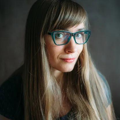 close-up portrait of a real woman wearing eyeglasses over dark background