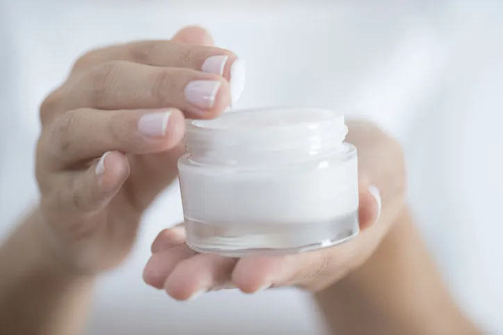 female hand holding moisturizer in hand, horiztonal