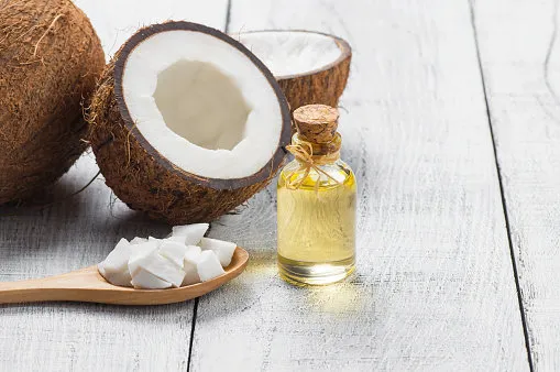 glass bottle of coconut oil with fresh coconut fruit on wooden rustic background, alternative theraphy medicine concept, cocos nucifera