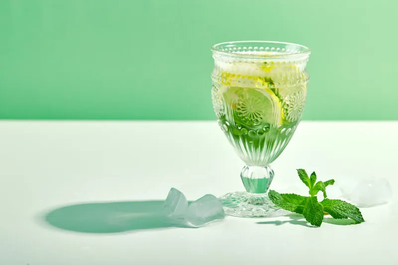 summer drink, fresh lemonade with mint, lemon and ice in wine glass mint infused water, alcoholic or non-alcoholiccocktail, detox drink or lemonade place for text