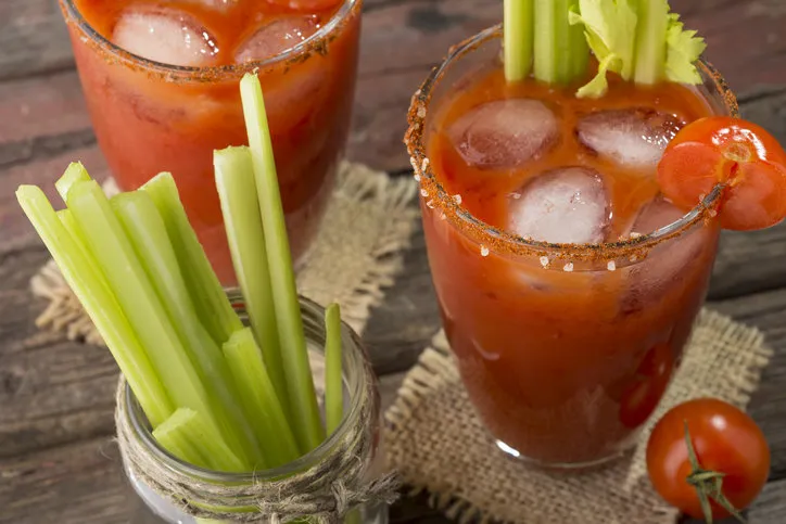high angle view of a bloody mary cocktail with vodka, lemon and tomato juice, tabasco sauce and ice cubes decorated with celery leaves