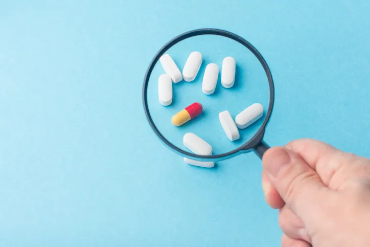 concept - pharmaceutical testing, testing of medicines, magnifying glass, tablets on a blue background doping control