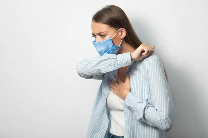 coronavirus respiratory hygiene sick girl coughing into elbow wearing protective medical mask having covid-19 pneumonia standing over white background copyspace