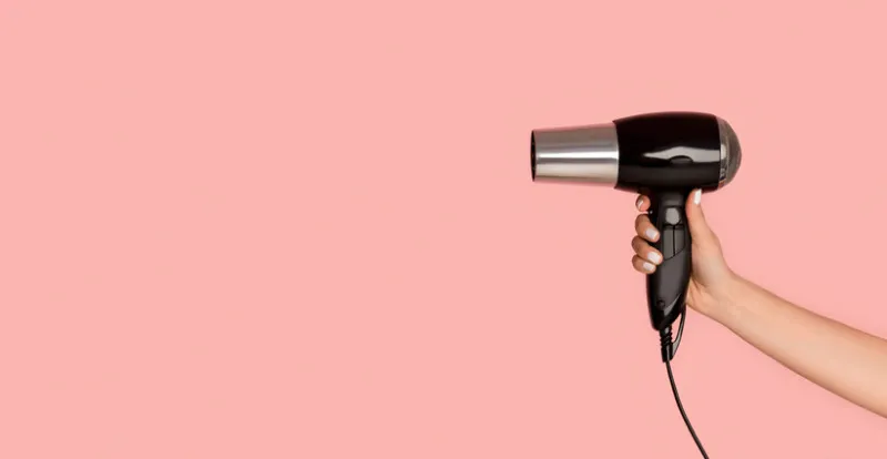 unrecognizable girl showing hairdryer on pink background, empty space panorama