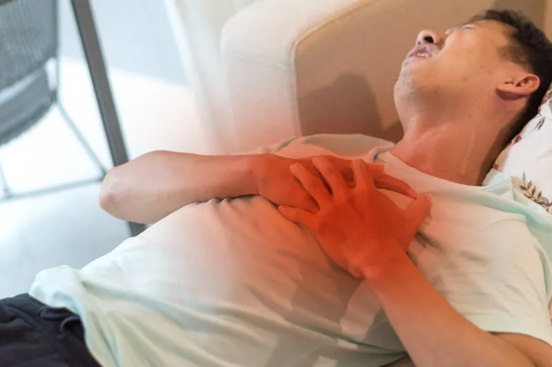 manâs hand on chest with red spot as suffering on chest pain male lay down suffer from heart attack,lung problems,myocarditis, heart burn,pneumonia or lung abscess, pulmonary embolism day