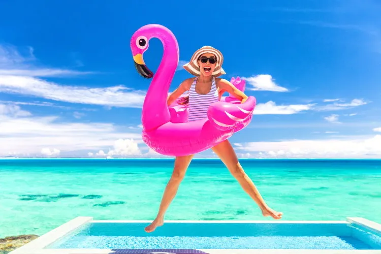 summer vacation fun funny woman jumping with flamingo swimming pool float around waist excited of tropical hotel holiday
