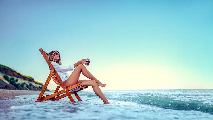 pretty woman relaxing on a lounger beach and drinks soda water summer vacation concept