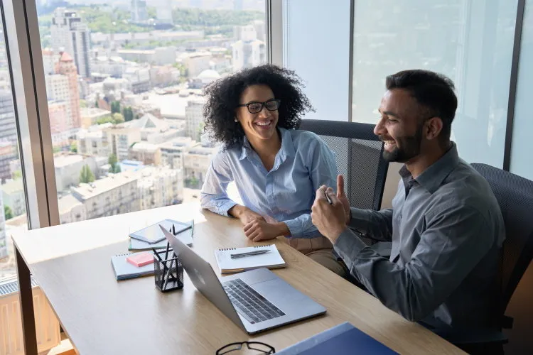 friendly happy multiethnic coworkers male indian and black female sitting at desk with laptop working together discussing successful project corporate business collaboration concept top view