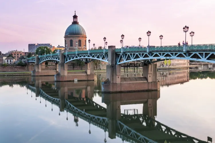 saint-pierre bridge reflecting in garonne river and dome de la grave at sunset in toulouse, france