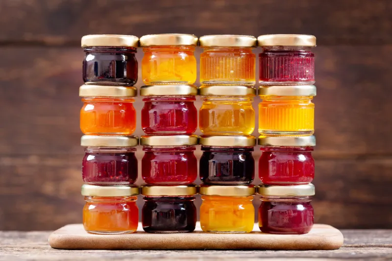 various jars of fruit jam on wooden table