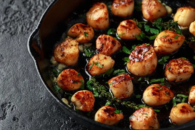 scallops seared in garlic and parsley butter served in cast iron skillet