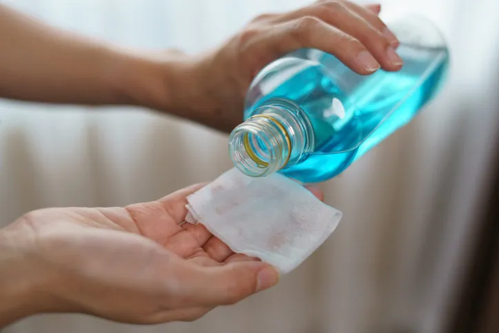pouring ethyl alcohol from bottle into a cotton piece for corona virus or covid-19 protection