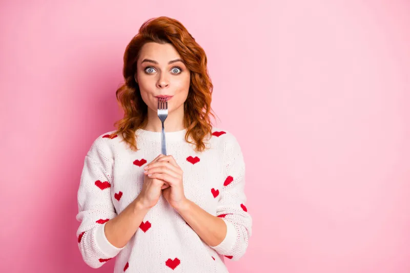 close-up portrait of her she nice attractive pretty funny hungry, cheerful wavy-haired girl licking fork want wish tasty yummy meal seduction healthy regime isolated on pink pastel color background