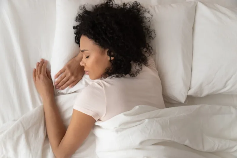 healthy serene young african american girl sleeping well in comfortable cozy fresh bed on soft pillow white linen orthopedic mattress, calm sleepy black woman enjoy peaceful sleep at home, top view