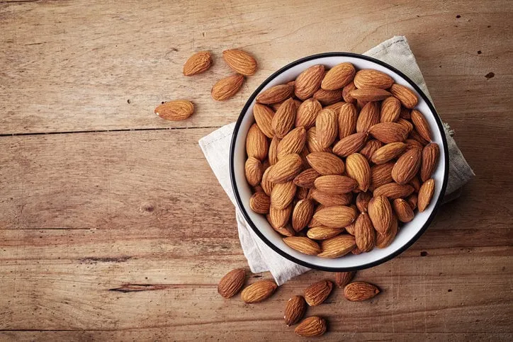 white bowl of almonds on wooden background