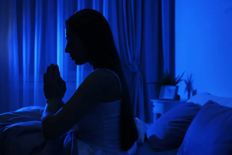 young woman praying in dark room at night bedtime