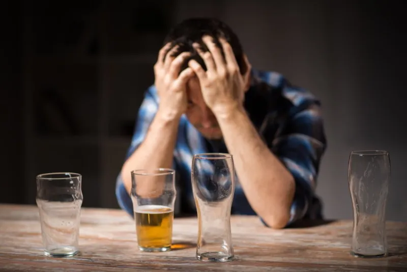 alcoholism, alcohol addiction and people concept - male alcoholic drinking beer from glass at night