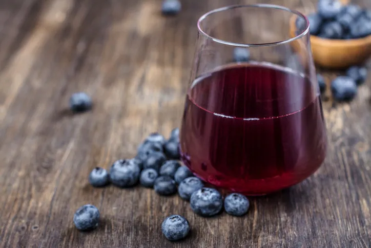 fresh blueberry juice with berries on wooden background