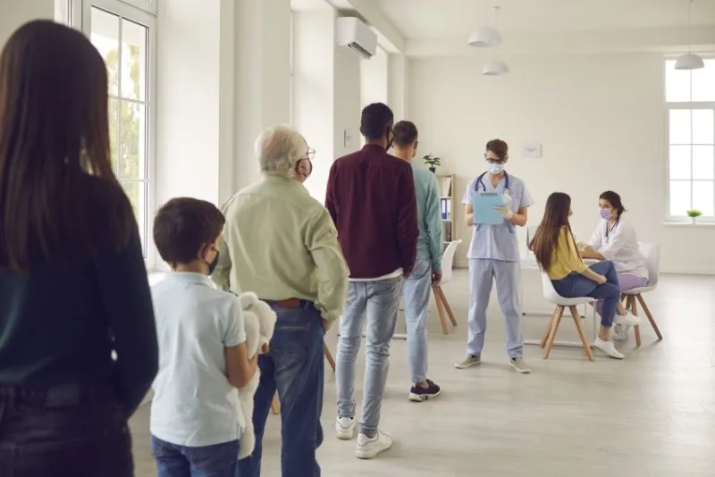 diverse people lining up waiting for their turn to get shots at the hospital vaccination center young men and women, senior citizens and kids standing in queue for antiviral covid-19 or flu vaccine