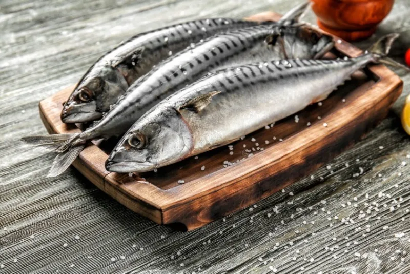 board with tasty raw mackerel fish on wooden table