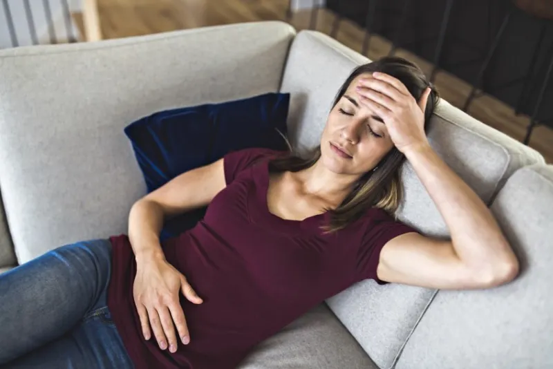 a sick woman lying on sofa in the living room with stomach ache