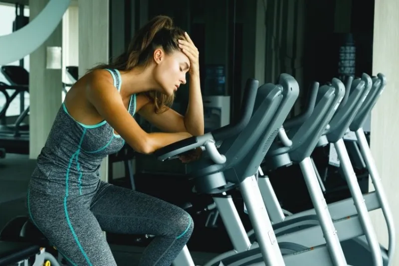 woman on the stationary bike with overtraining symptoms