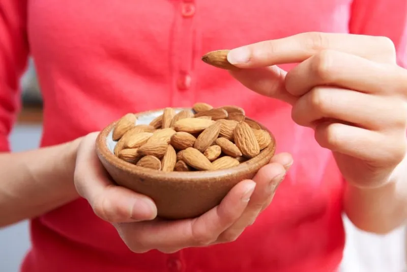 woman eating healthy snack of almonds