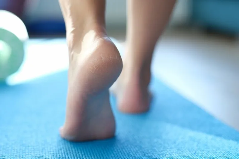 barefoot dry feet make a step on a sports mat, rear view, close-up rough skin of the feet, cracked heels