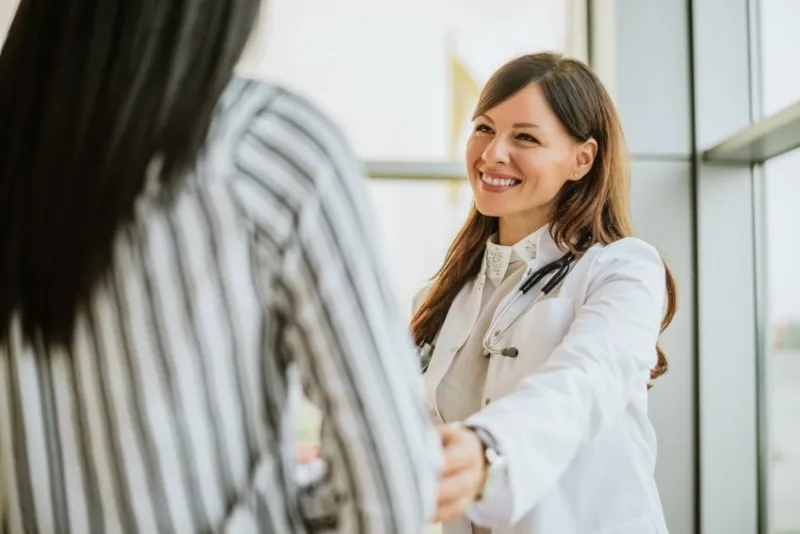 female doctor talking and touching woman patient for encouragement