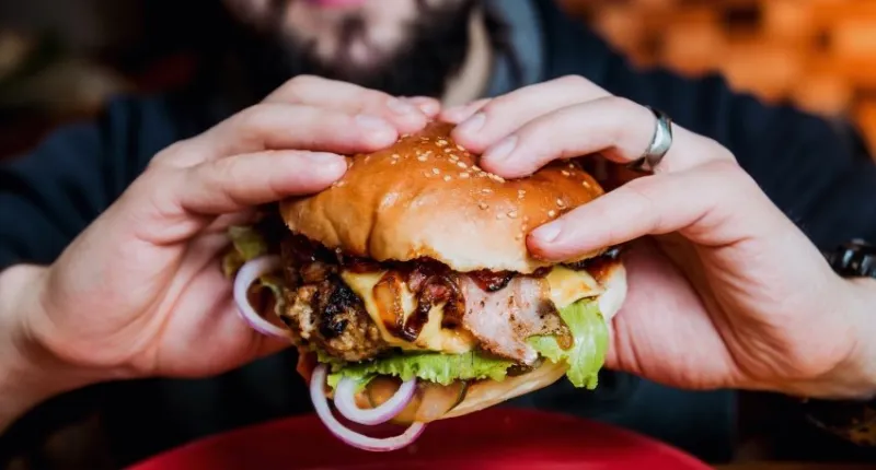 young man eating a cheeseburger restaurant