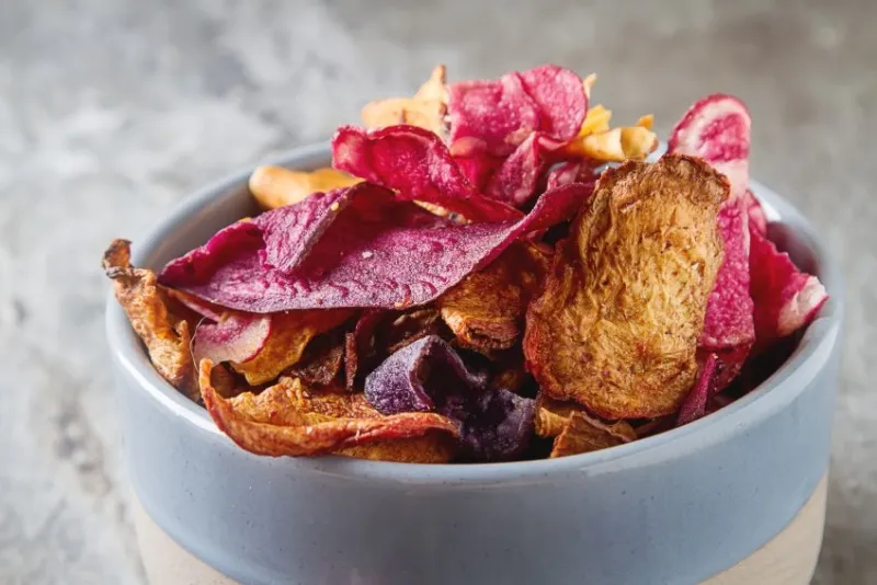 beet and carrot salty chips in an old blue plate stone background