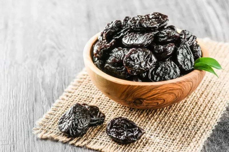 fresh prunes in wooden bowl prunes on stone dark table prunes healthy food dried plums