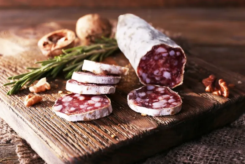 french salami on cutting board on sackcloth napkin on wooden background