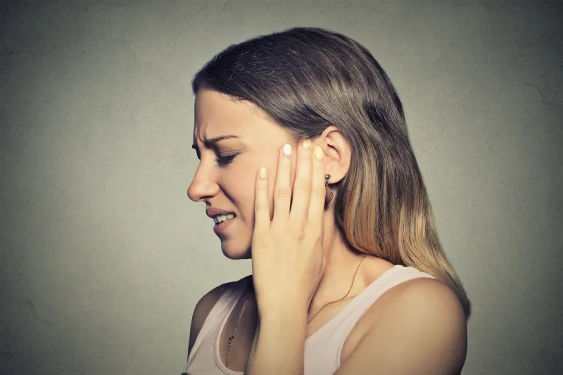 tinnitus closeup side profile sick young woman having ear pain touching her painful head isolated on blue background