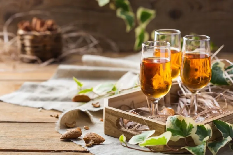 holidays, alcohol drink, beverage, digestif concept italian almond liquor amaretto on a wooden table