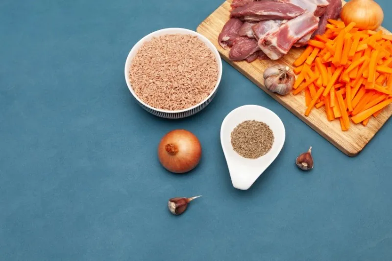 raw food, pilaf ingredients for pilaf, meat lamb, devzira rice, cumin, garlic and carrots on wooden cutting board oriental cuisine