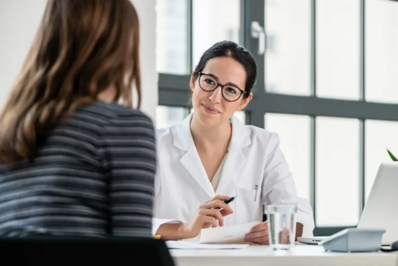 female physician listening to her patient during consultation while sitting down in the office of a modern medical center
