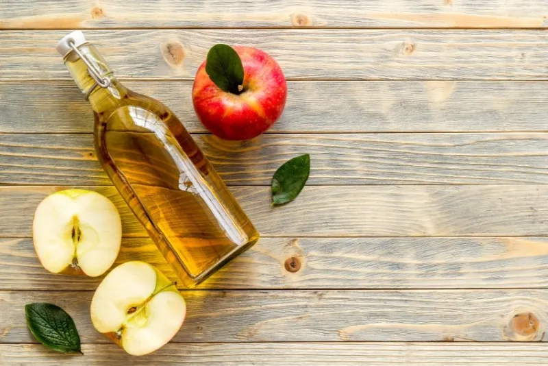 bottle of organic apple cider vinegar with red apples