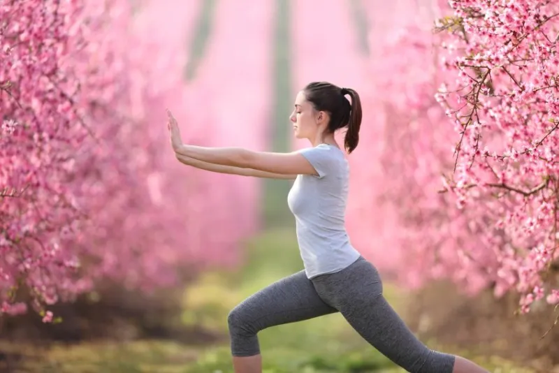 side view portrait of a woman doing tai chi exercise in a pink flowered field