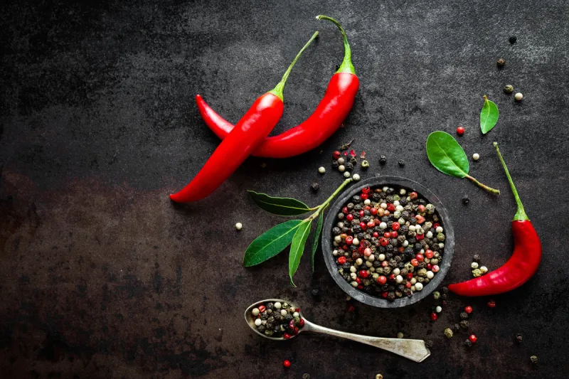 red hot chili pepeprs and peppercorns on black metal background, top view