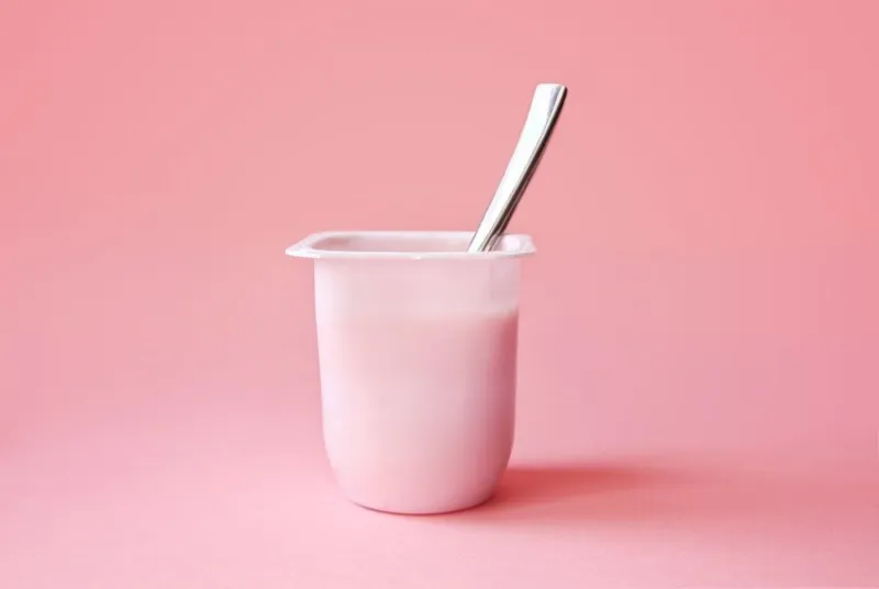 delicious strawberry yogurt or pudding in white plastic cup on pink background with copy space strawberry pink yoghurt with spoon in it minimal style